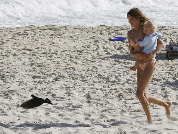 A sombra de Natalia Vodianova se confunde com a do pombo que ela persegue com o filho no colo pelas areias de Ipanema. Alguém de α Centauri que conseguisse essa foto capturando nacos de sinais de nossos satélites não entenderia nada.